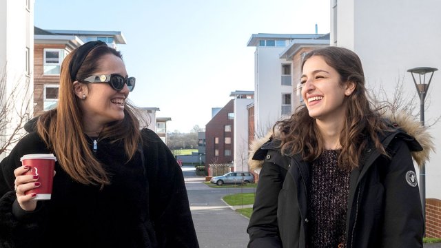 Two students laughing together whilst walking through Manor Park campus