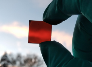 scientist holds bendy solar cell up to light