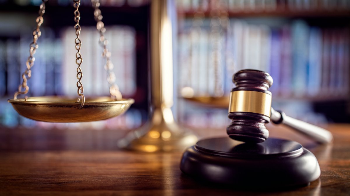 The image shows a gavel and scales of justice in a legal office