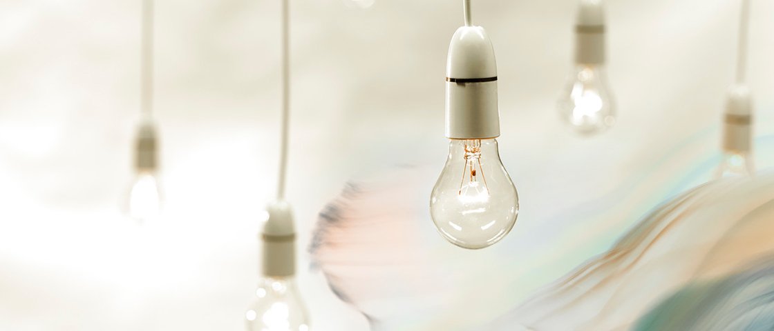 Several hanging white bulbs against a white background with an ethereal figure to the right 