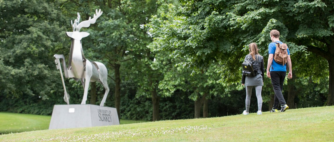 Students walking past stag sculpture