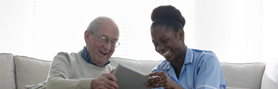 Elderly man using a tablet alongside nurse