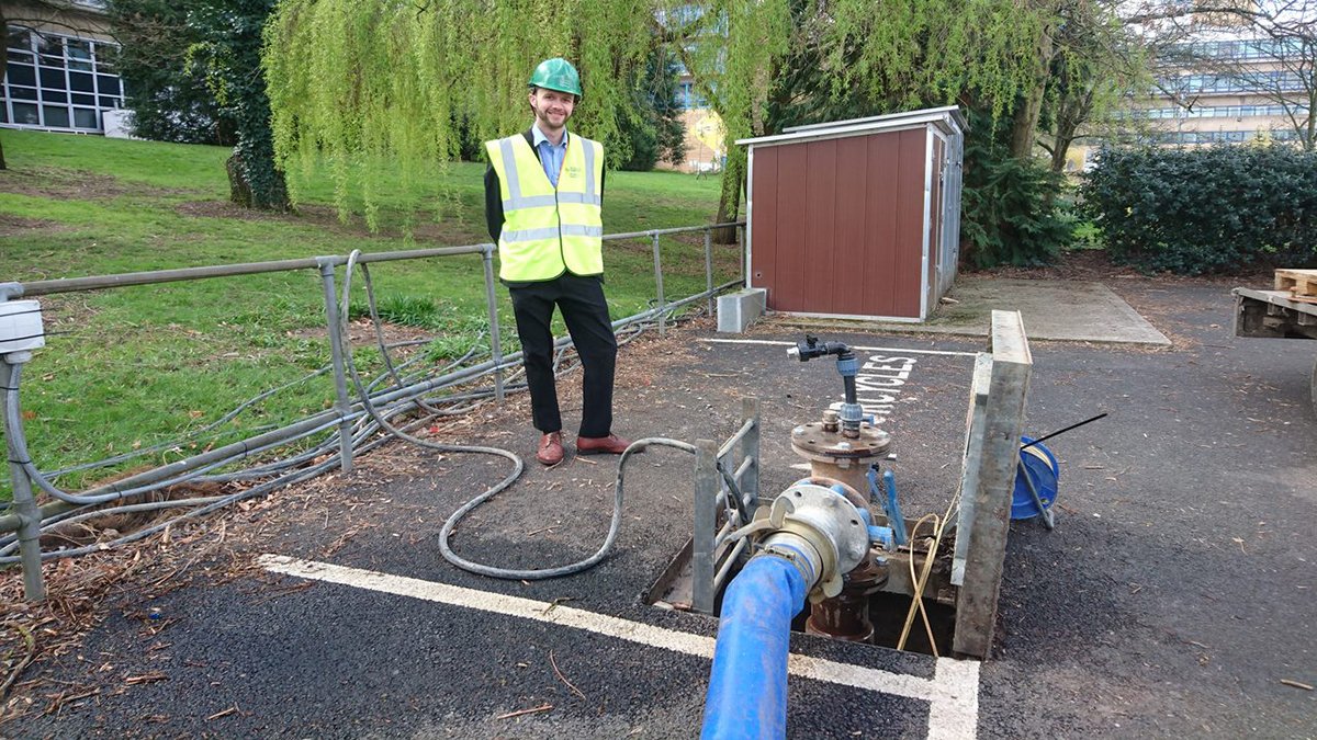 PhD student James Daly standing next to a borehole on Stag Hill Campus