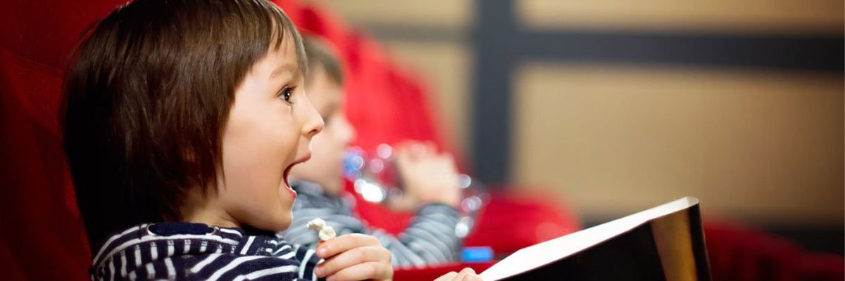 Child holding a piece of popcorn with his mouth open