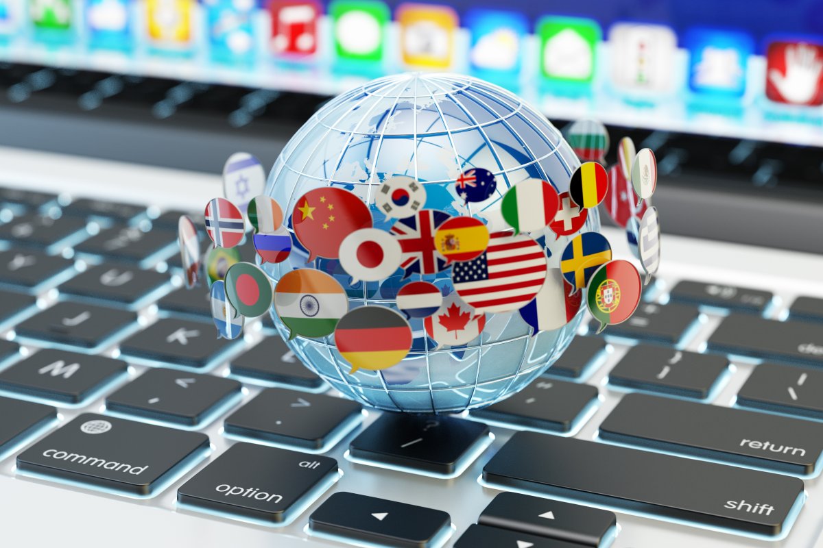 World globe with several country flags around it, sitting on top of a laptop keyboard