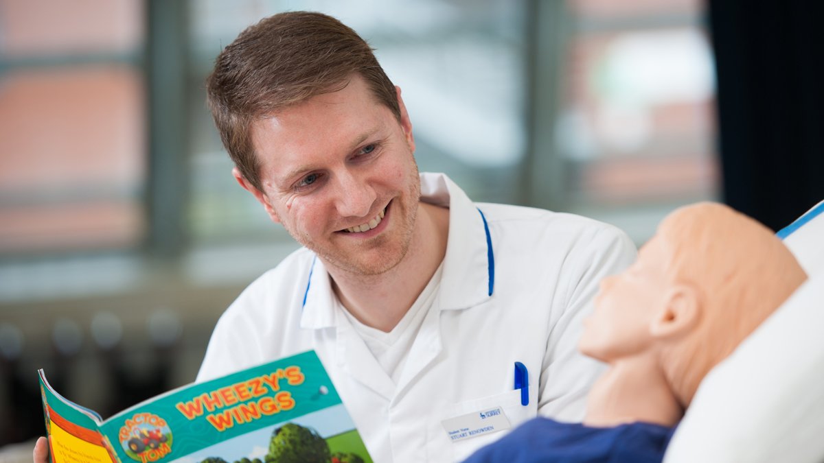 Trainee children's nurse, Stuart Renowden, reading a book to a child mannequin