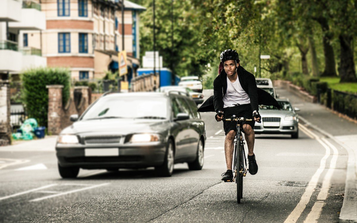 A cyclist on an urban road is overtaken by a car