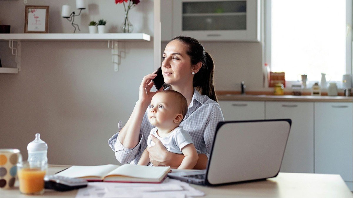 Mother working from home holding baby