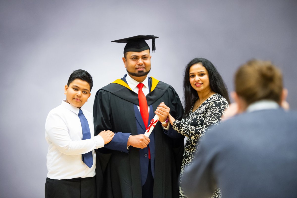 A graduand having their photo taken with their family