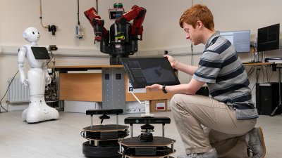 Man holding tablet that is connected to a robot