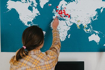 A women is sticking a pin in a world map