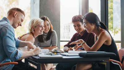 Group of people sat at table with their books talking together