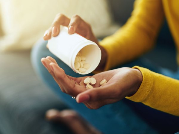 Person putting tablets from bottle into their hand