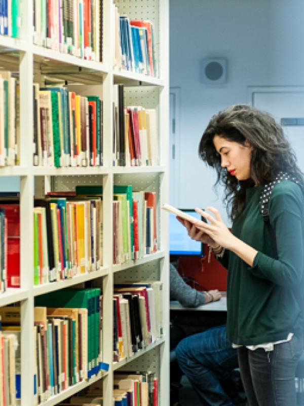 Female student browsing books in the University of Surrey library