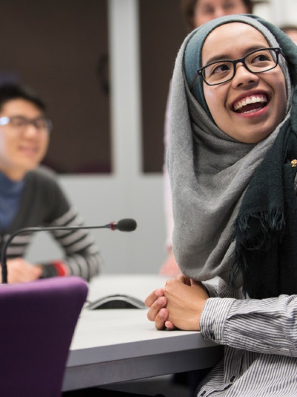 A group of students laughing together in a classroom