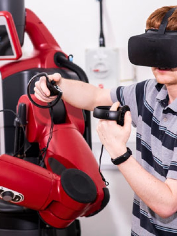 Student wearing virtual reality headset working with a robot