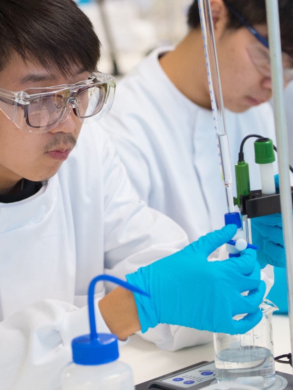 Student turning a lever to release liquid from a tube into a beaker