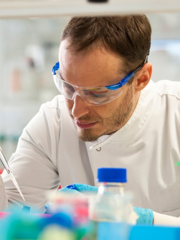 Student in a lab coat using a pipette