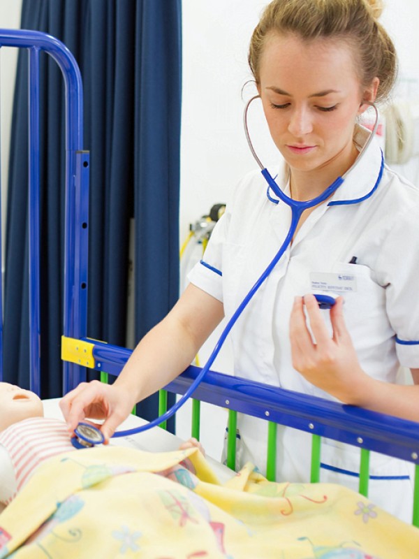 Student nurse checking heartbeat of child mannequin