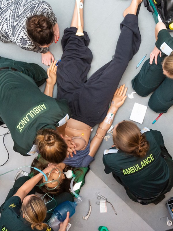 Birdseye view of trainee paramedics providing treatment to a medical manikin