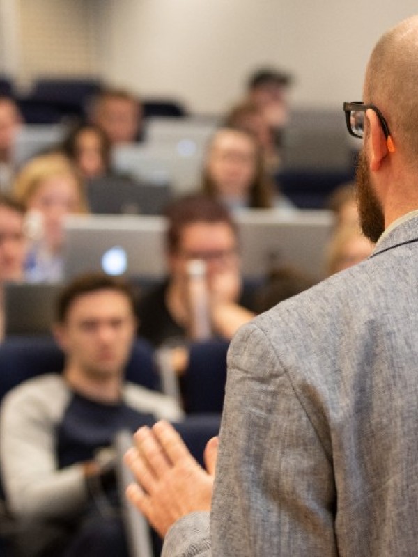 Lecturer speaks to students a busy lecture hall