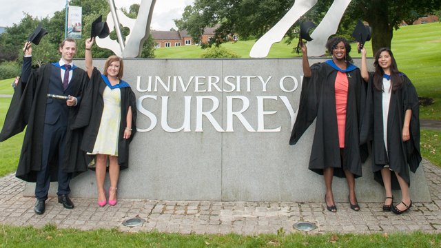 Graduates standing in front of the stag on campus