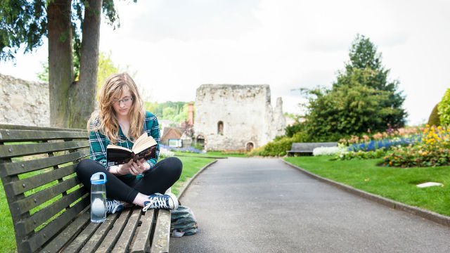 A student reading by Guildford castle
