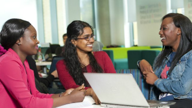 Three postgraduate students talking in the library.