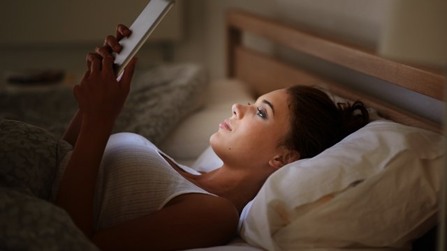 Female in bed using tablet