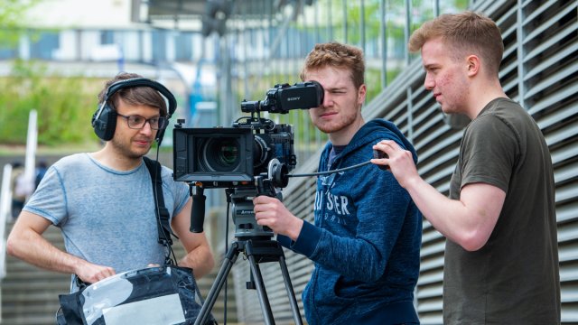 Three male students using a camera