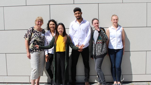 Group of uni staff standing in front of a wall