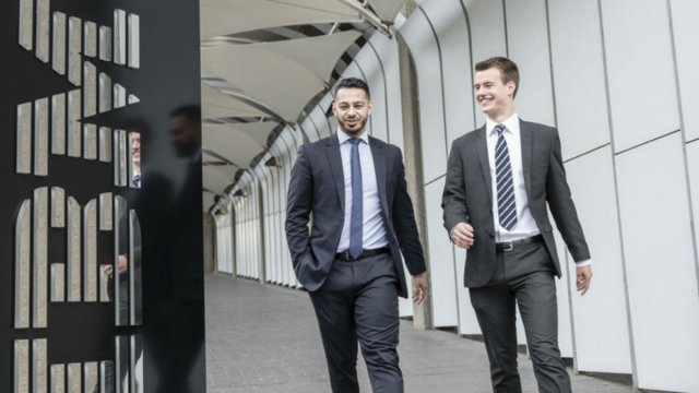 Two Surrey students walk outside the IBM sign during their work placement