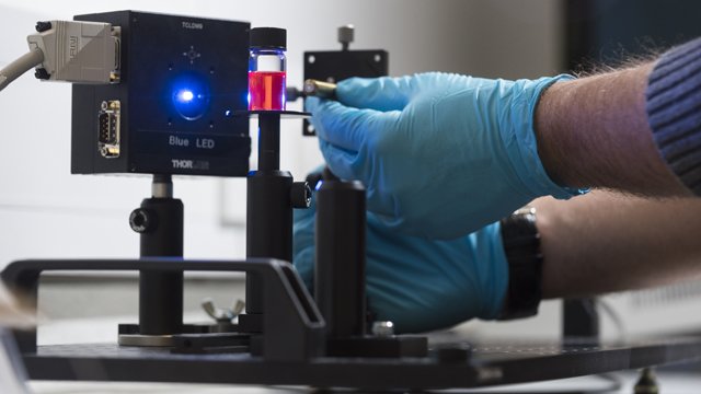 Person wearing rubber gloves using physics equipment