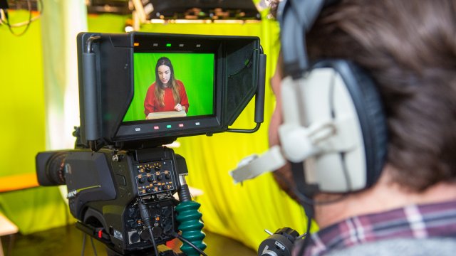 Male student looking at camera screen whilst wearing a headset.