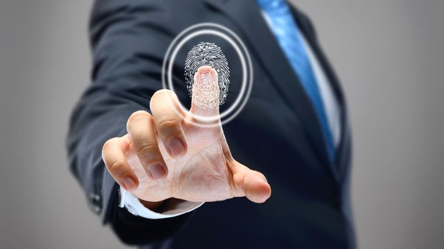 Man pressing finger against glass with fingerprint