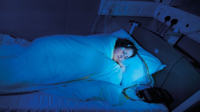 Woman sleeping in a bed with monitors and a blue light on