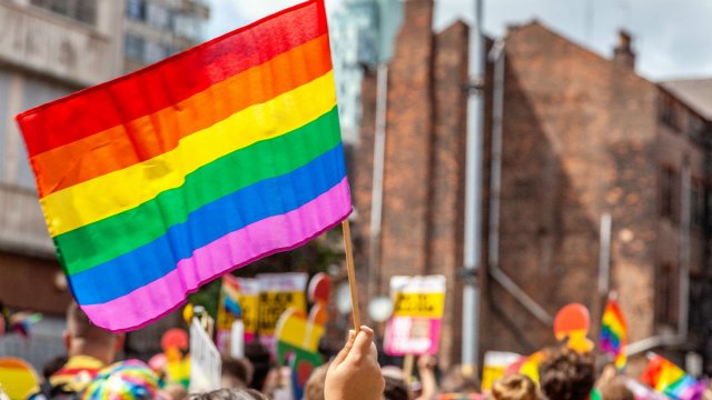 An LGBTIQ flag is waved in a crowd of people