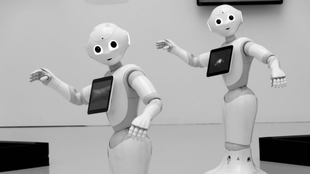Two white robots waving
