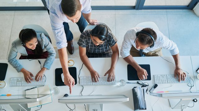 Male teacher pointing at student's computer screen