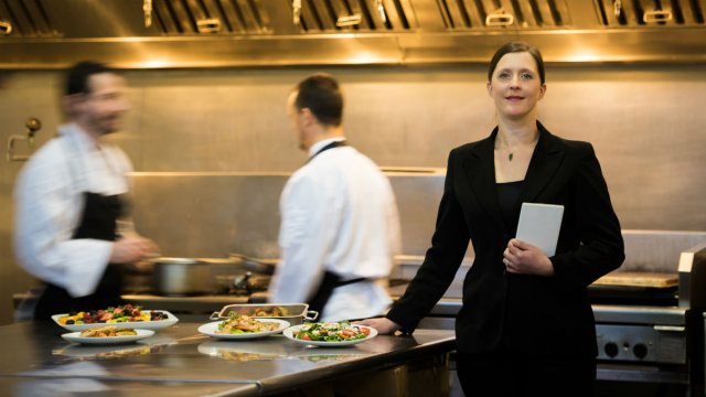 A restaurant manager stands in a busy hotel restaurant kitchen