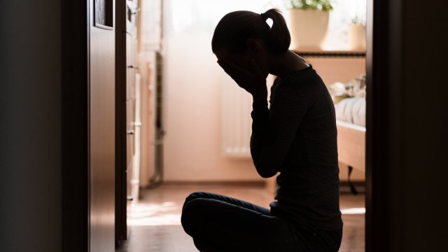 The silhouette of a woman with her head in her hands sat on the floor