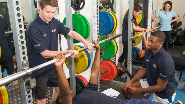 Students spotting each other using weights