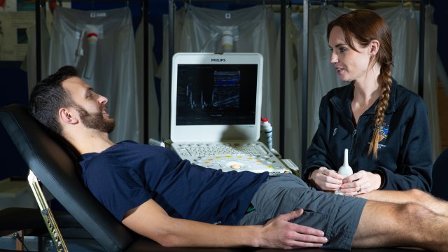 Student laying on couch having leg scanned