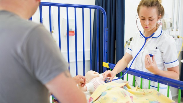 Student nurse checking heartbeat of child mannequin