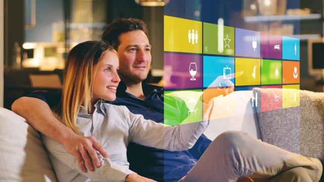 Couple sat on sofa looking at a virtual screen