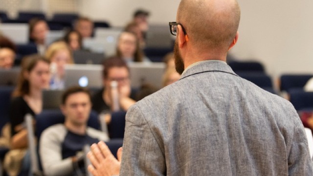 Lecturer speaks to students a busy lecture hall