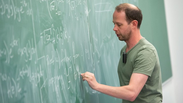 Lecturer writing on chalk board
