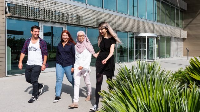 Group of postgraduate students walking through campus together