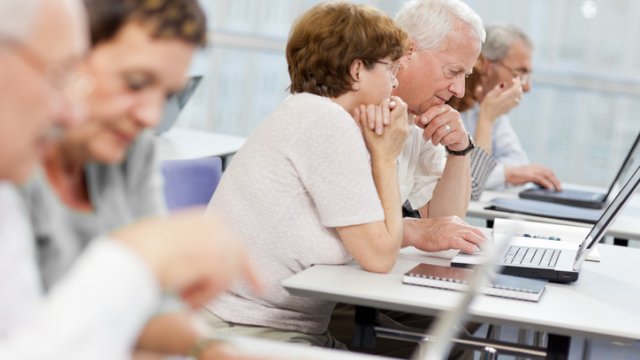 A group of elderly people take part in a computer class