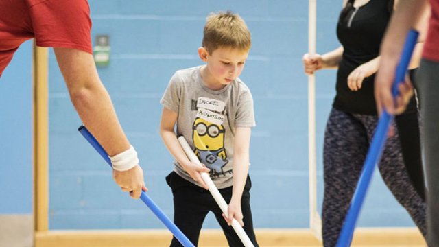 Kid playing hockey with some adults at the Surrey Sports Park